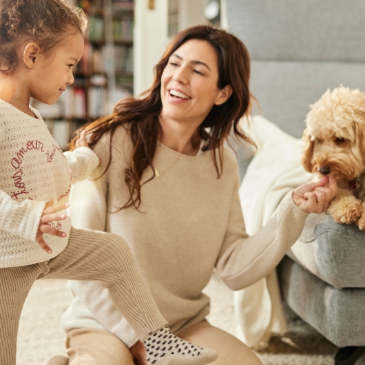 Frau mit kind auf dem arm die einen hund steichelt